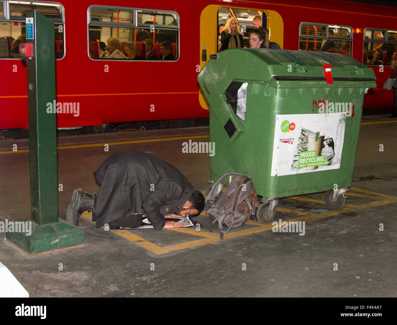 Londres, Royaume-Uni. 19 octobre 2015. Un homme effectue une prière islamique à côté d'un bac de recyclage sur une plate-forme du train à la gare de Waterloo London Crédit : amer ghazzal/Alamy Live News Banque D'Images