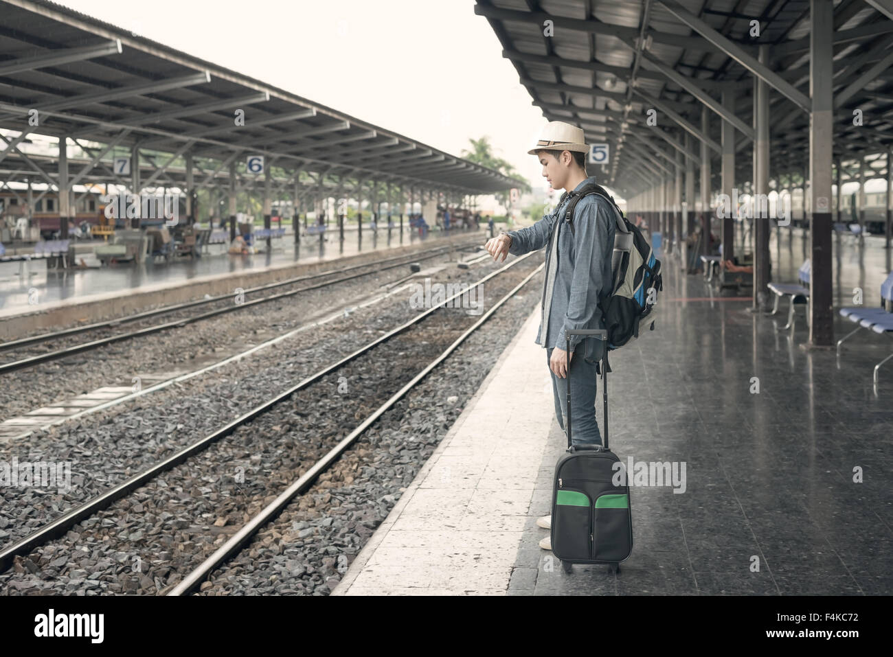 Retard de train. Les jeunes hommes à la recherche de sa montre en attendant à la station de train Banque D'Images