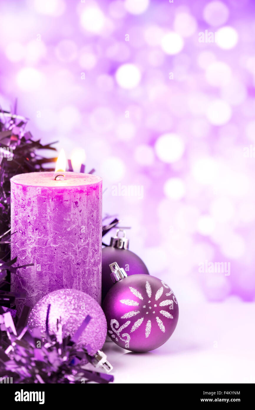 Boules de Noël pourpre et argent et une bougie devant defocused lights violet et blanc. Banque D'Images