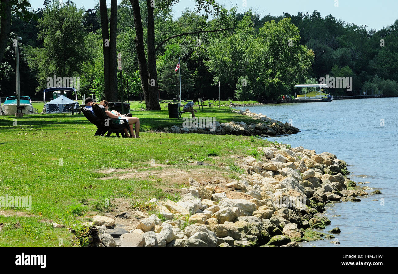 Rive et de couple assis sur des chaises le long d'une rivière Banque D'Images