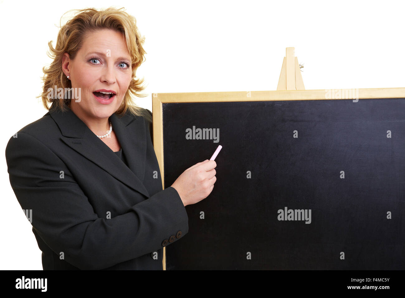 Happy woman in jacket pointant sur tableau noir Banque D'Images