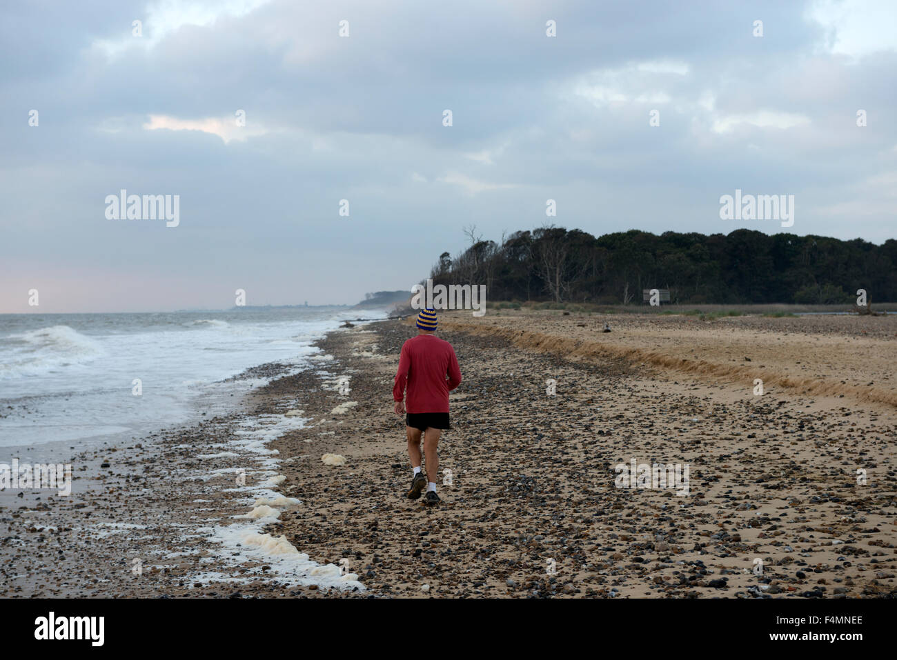 Man jogging on beach Benacre, Suffolk, UK. Banque D'Images