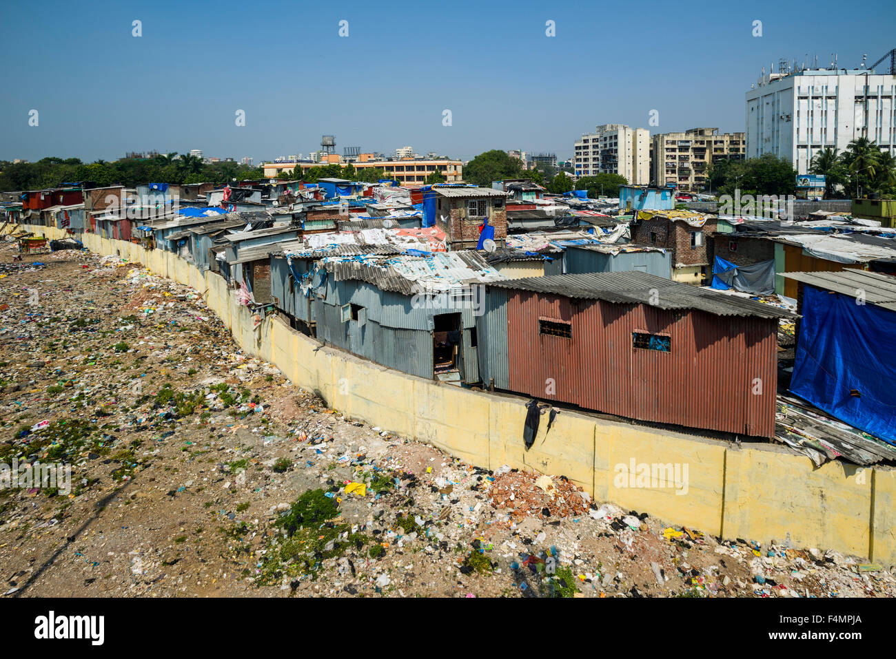 Un bidonville derrière un mur et avec de nouveaux bâtiments dans la distance Banque D'Images