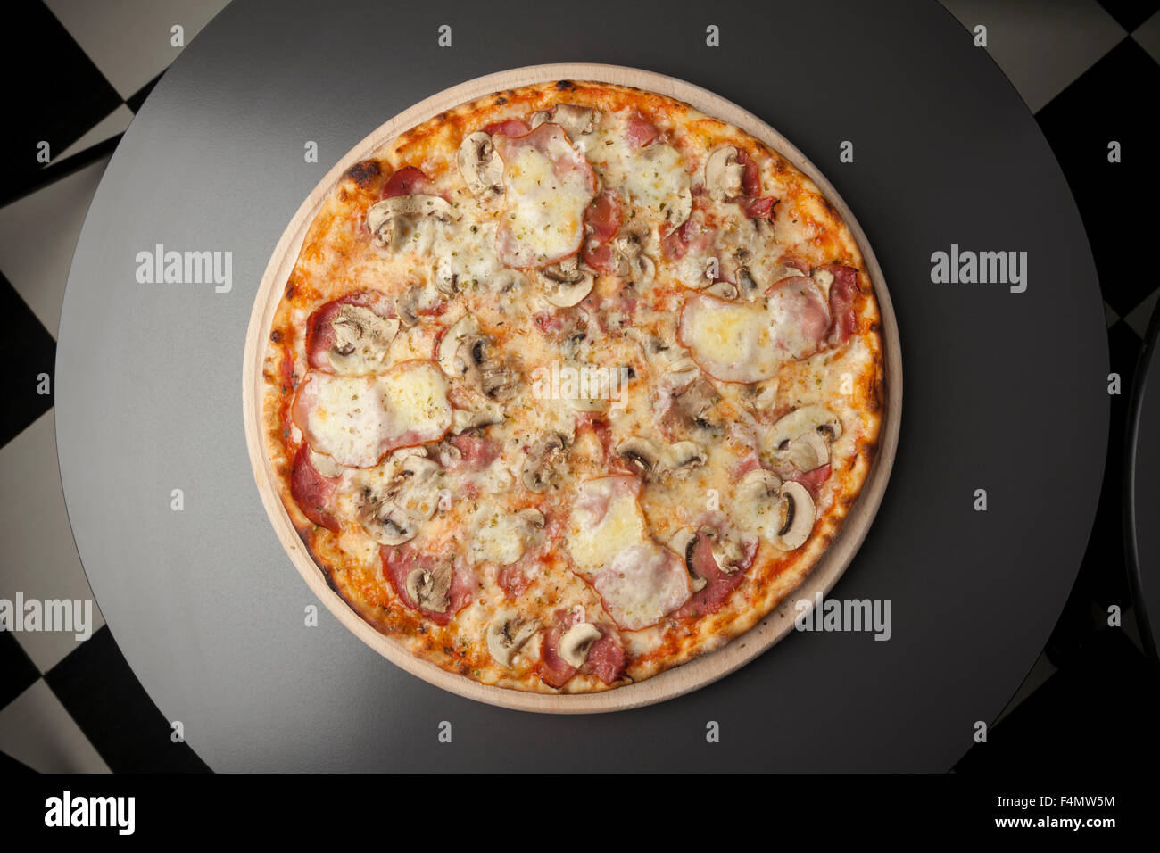 La pizza sur une plaque de bois avec des champignons, du jambon fumé et mozzarella Banque D'Images