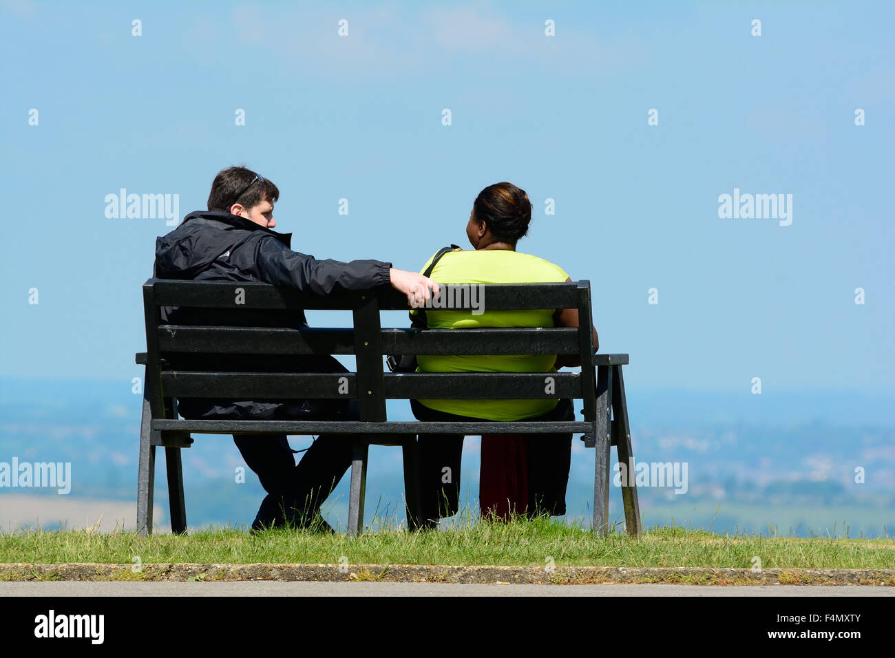 Caucasian man sitting on bench avec femme afro-antillaise Banque D'Images