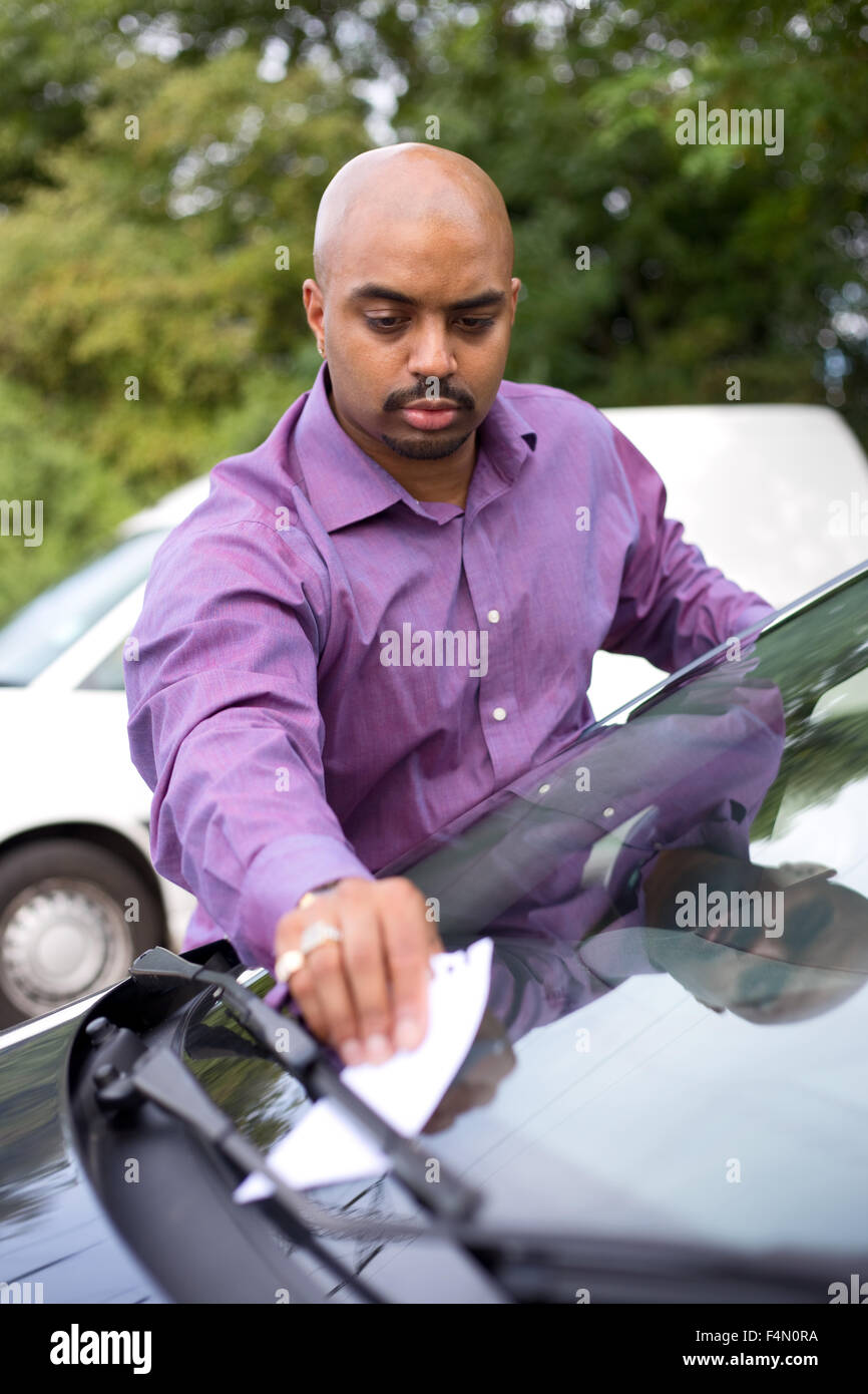 Man putting une note sur un pare-brise de voiture Banque D'Images