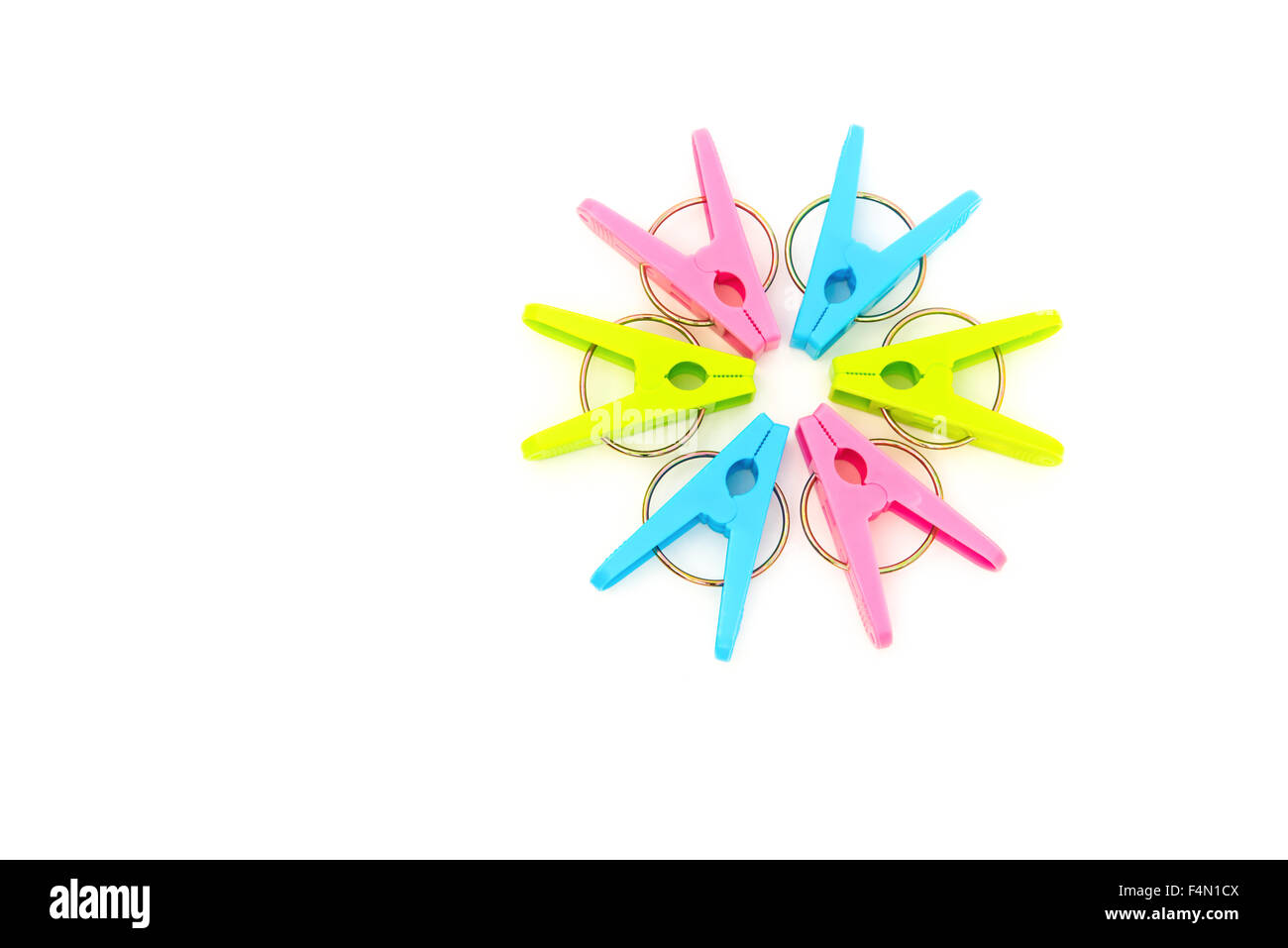 Pinces à linge colorées s'alignent comme un cercle sur un fond blanc Banque D'Images