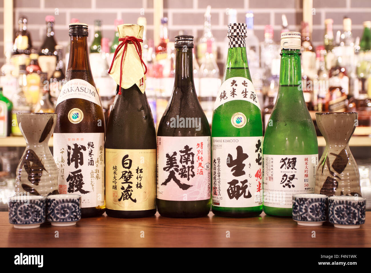 Une rangée de bouteilles Saki Japonais sur un bar haut de saké verres Banque D'Images