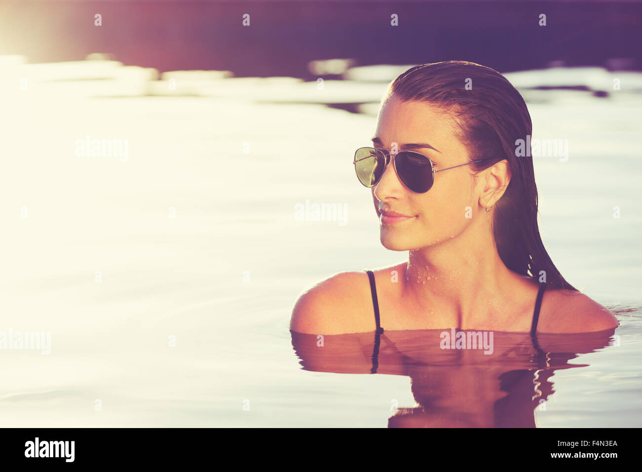 Belle jeune femme se détendre dans la piscine au coucher du soleil, la mode de vie De Luxe Resort Banque D'Images