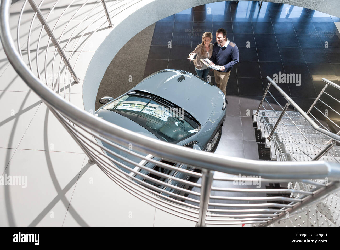 Couple looking at new car in showroom Banque D'Images