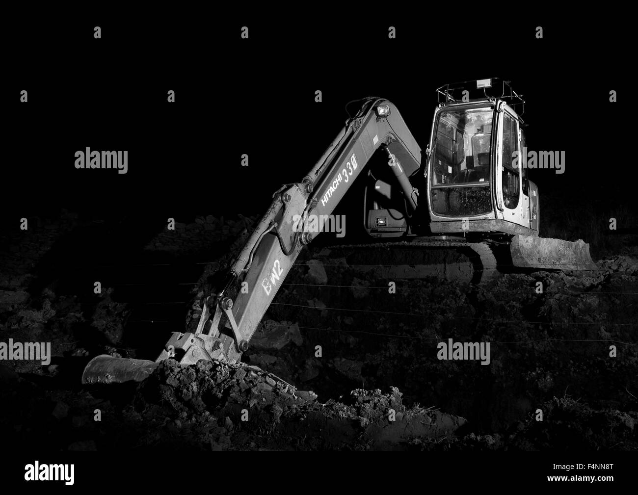 Digger excavateur/dans la nuit éclairée par la lumière de torches Banque D'Images