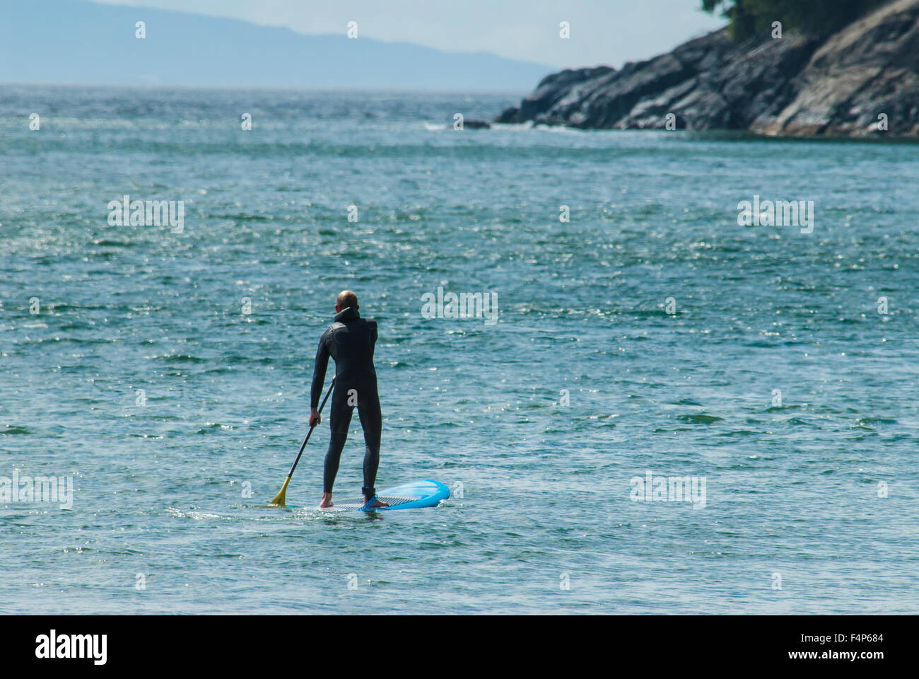 Un stand-up paddleboarder dans une combinaison de pagayer à China Beach sur l'île de Vancouver Banque D'Images