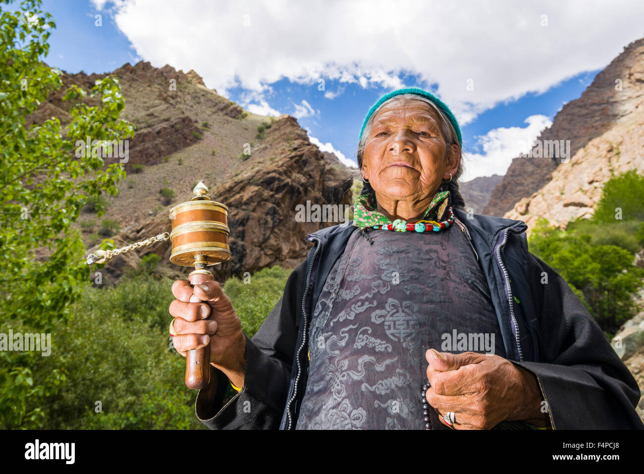 Une vieille femme ladakhis tourne une roue de prière dans une petite vallée au-dessus de hemis gompa Banque D'Images
