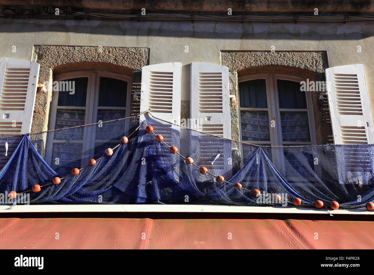 France, Bretagne, Concarneau, filets de pêche bleu pendants devant les fenêtres Banque D'Images