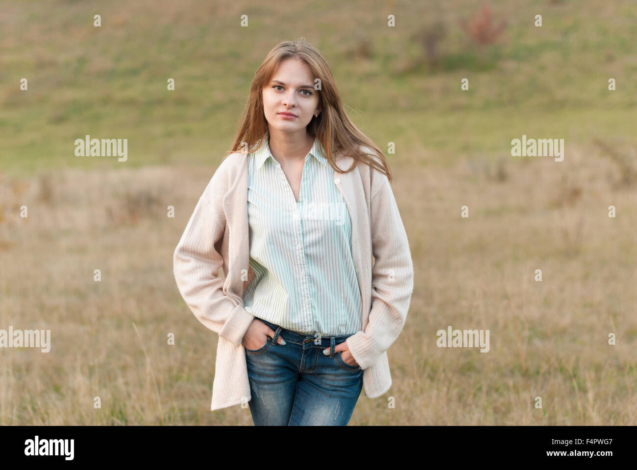 Belle jeune fille avec de longs cheveux de poser dans un pré. Banque D'Images