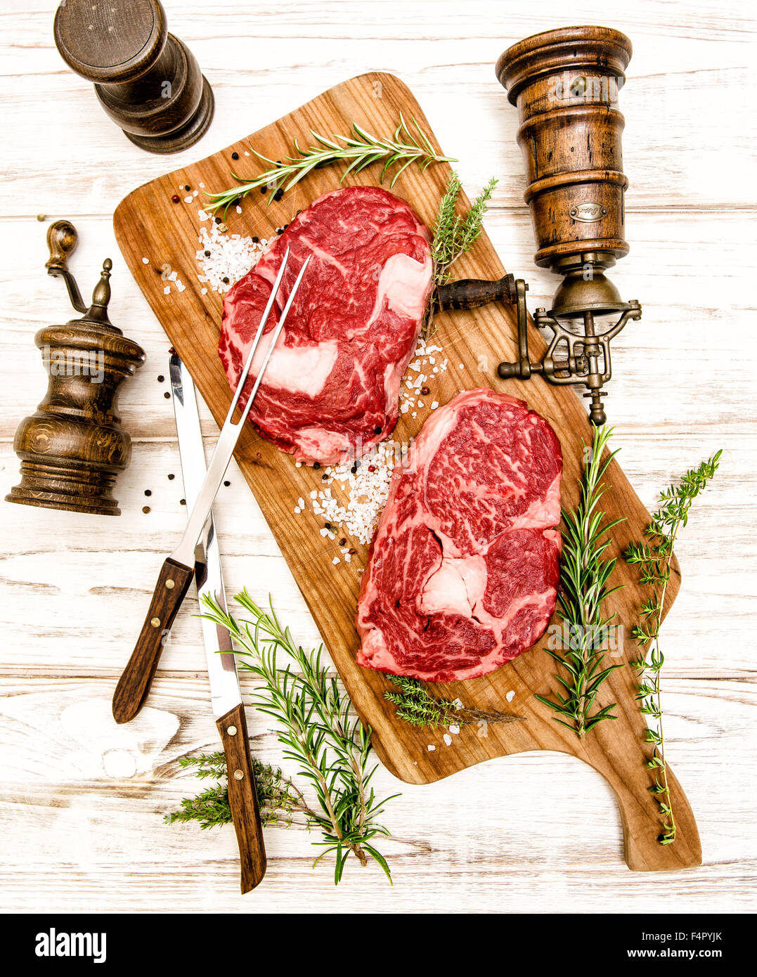 Matières de la viande fraîche aux herbes Steak de faux-filet sur fond de bois. Fourchette et couteau pour la préparation des aliments Banque D'Images