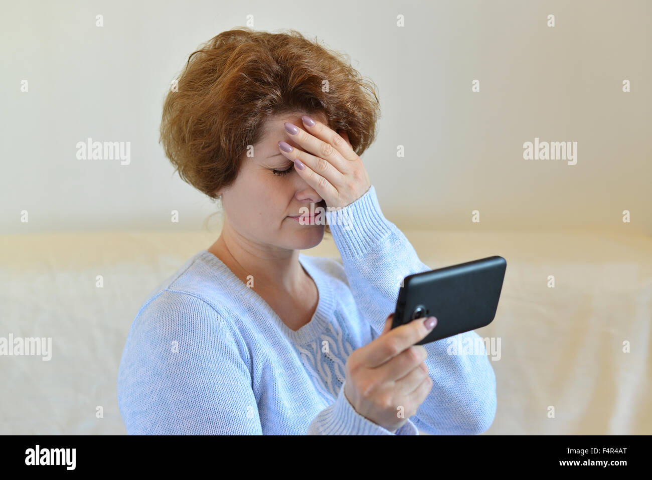 Femme en colère se lit SMS sur téléphone portable Banque D'Images