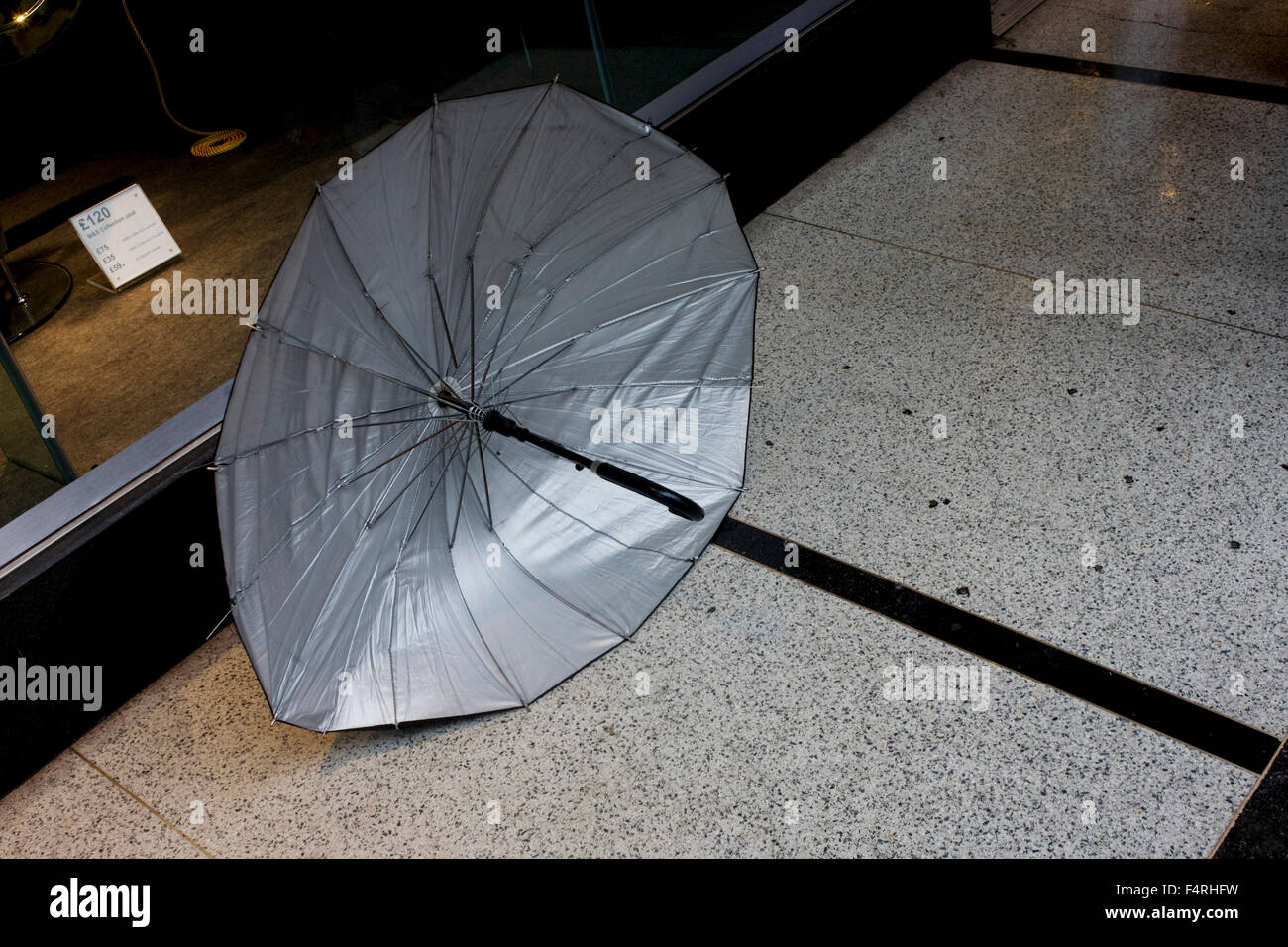 Détail d'un parapluie abandonné à l'extérieur d'une boutique au centre de Londres et la poursuite d'une ligne noire. Banque D'Images
