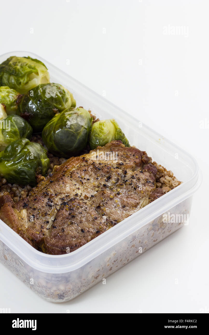 Escalopes de porc frit avec les choux de Bruxelles et le sarrasin dans une boîte à lunch. Banque D'Images