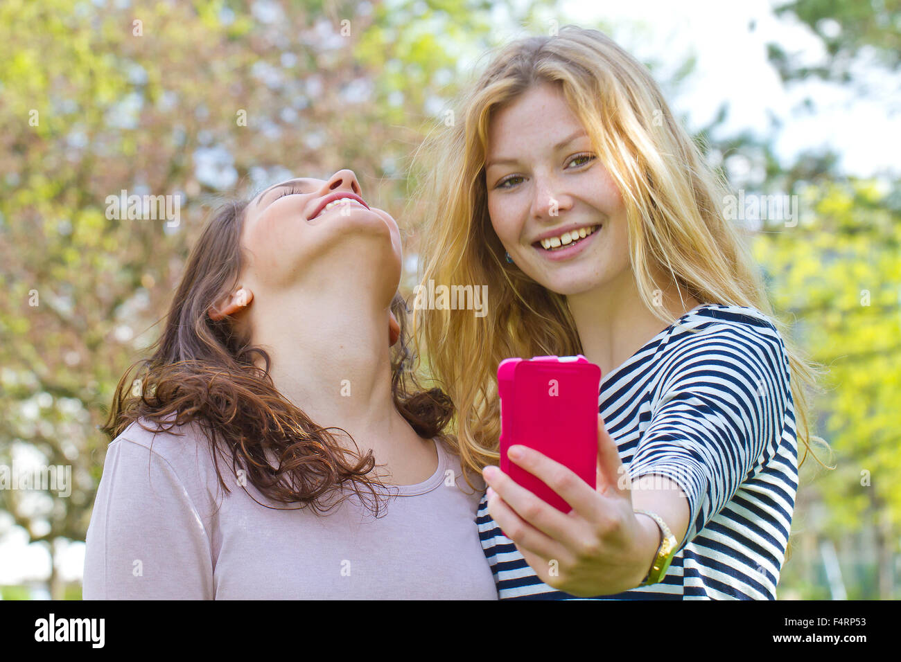 Deux jeunes filles en tenant un téléphone intelligent avec selfies Banque D'Images