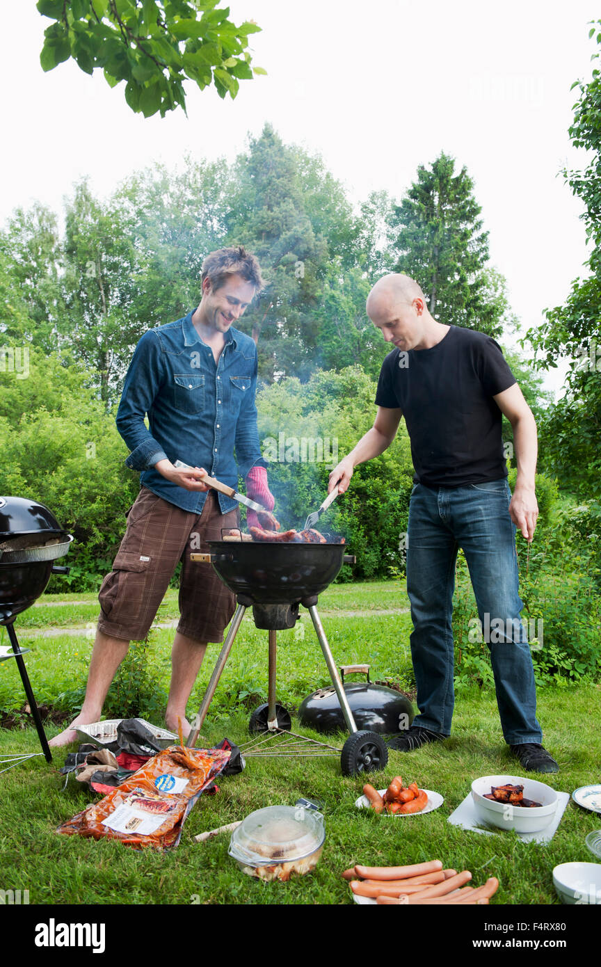 La Suède, l'océan, Kungälv, mi-hommes adultes ayant un barbecue dans la cour Banque D'Images