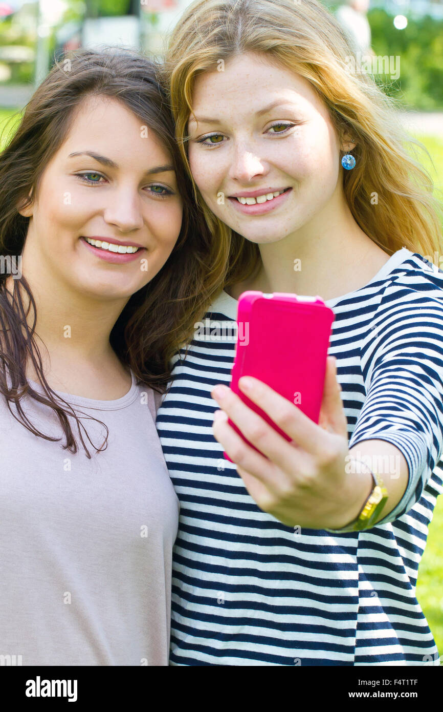 Deux jeunes filles en tenant un téléphone intelligent avec selfies Banque D'Images