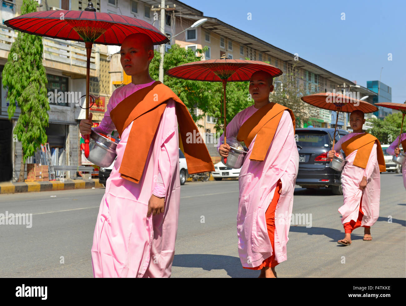 Nonnes novices marchant dans une rue principale collectant pour les almes, Mandalay, Myanmar, anciennement Birmanie, Asie du Sud-est Banque D'Images