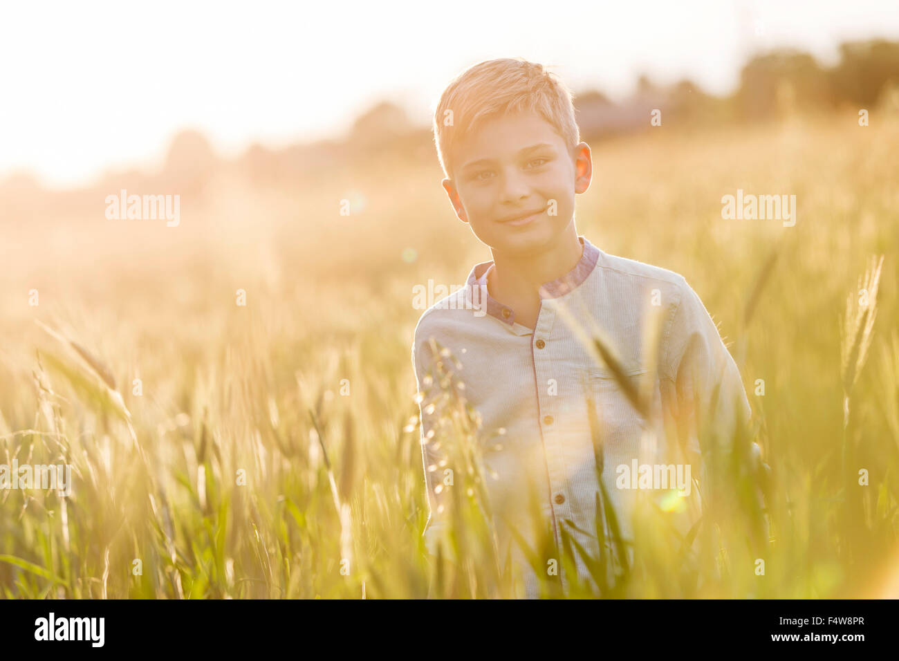 Portrait smiling boy en champ de blé rural ensoleillé Banque D'Images