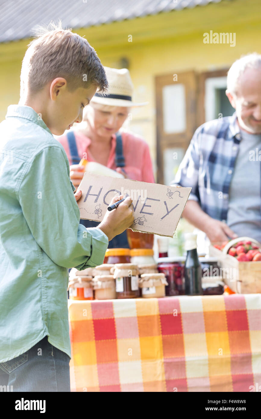 Boy drawing miel signe pour farmer's market stall Banque D'Images