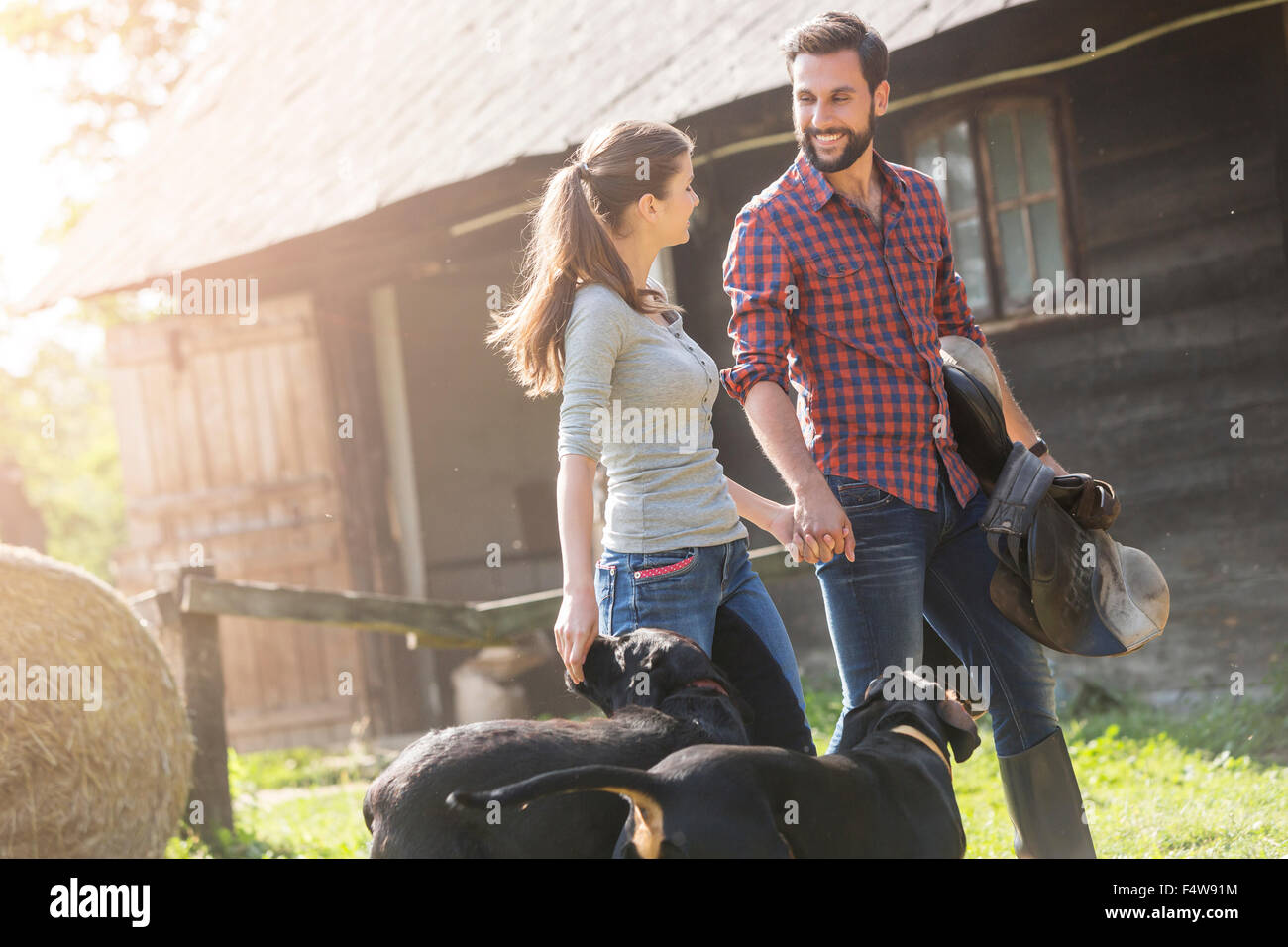 Couple avec selle et le chien se tenant la main en dehors de l'espace rural grange Banque D'Images