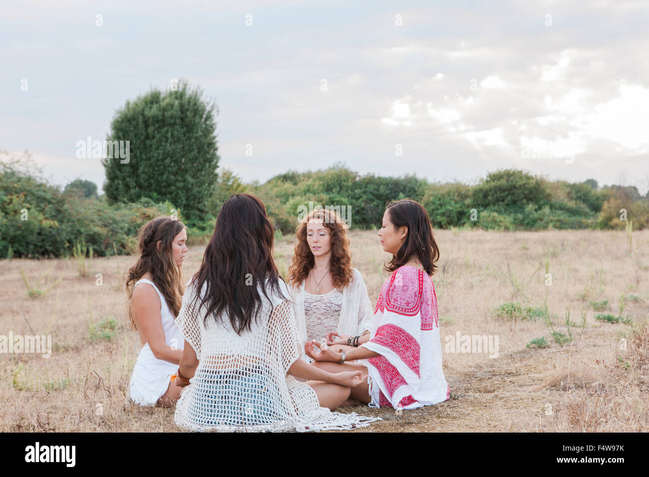 Les femmes Boho méditant dans circle in rural field Banque D'Images
