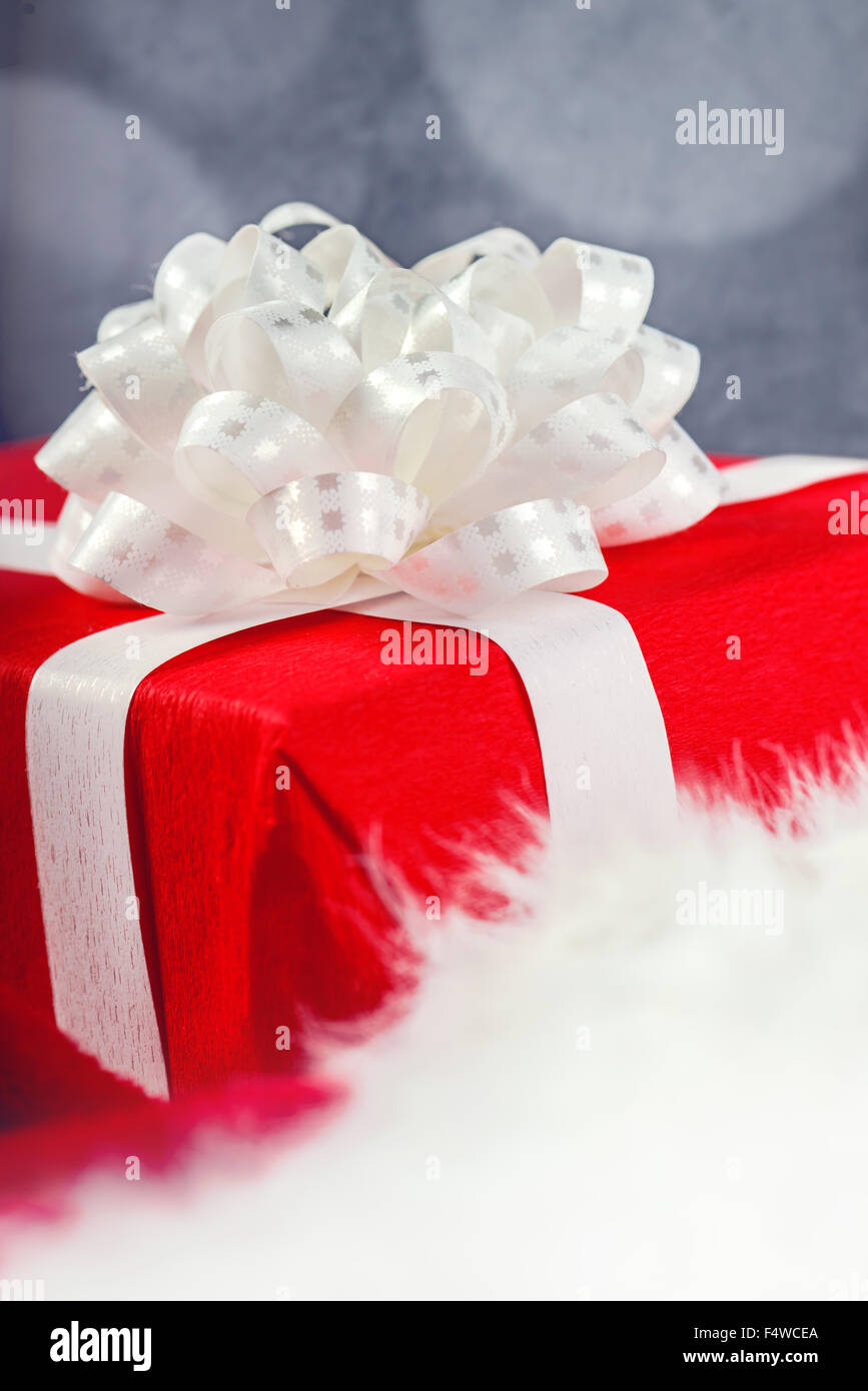 Cadeau ou présent enveloppé dans du papier rouge et attachés à un ruban blanc, selective focus Banque D'Images