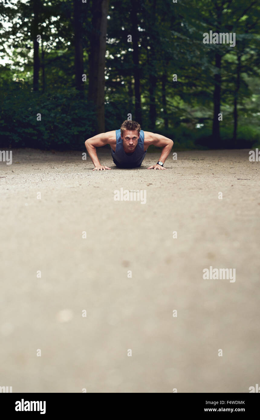 Portrait d'un jeune homme fit faire des tractions dans un parc dans le cadre de son régime d'exercice quotidien, avec premier plan copyspace Banque D'Images