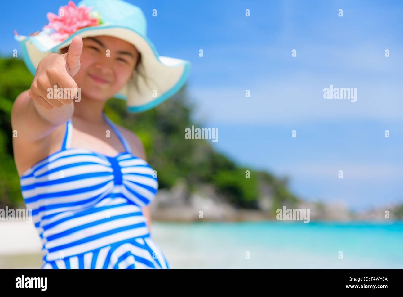Fille en bleu touristiques maillot blanc thumb up permanent faisant l'éloge de la beauté naturelle de la mer sur la plage durant l'été à l'île de Koh Miang Banque D'Images
