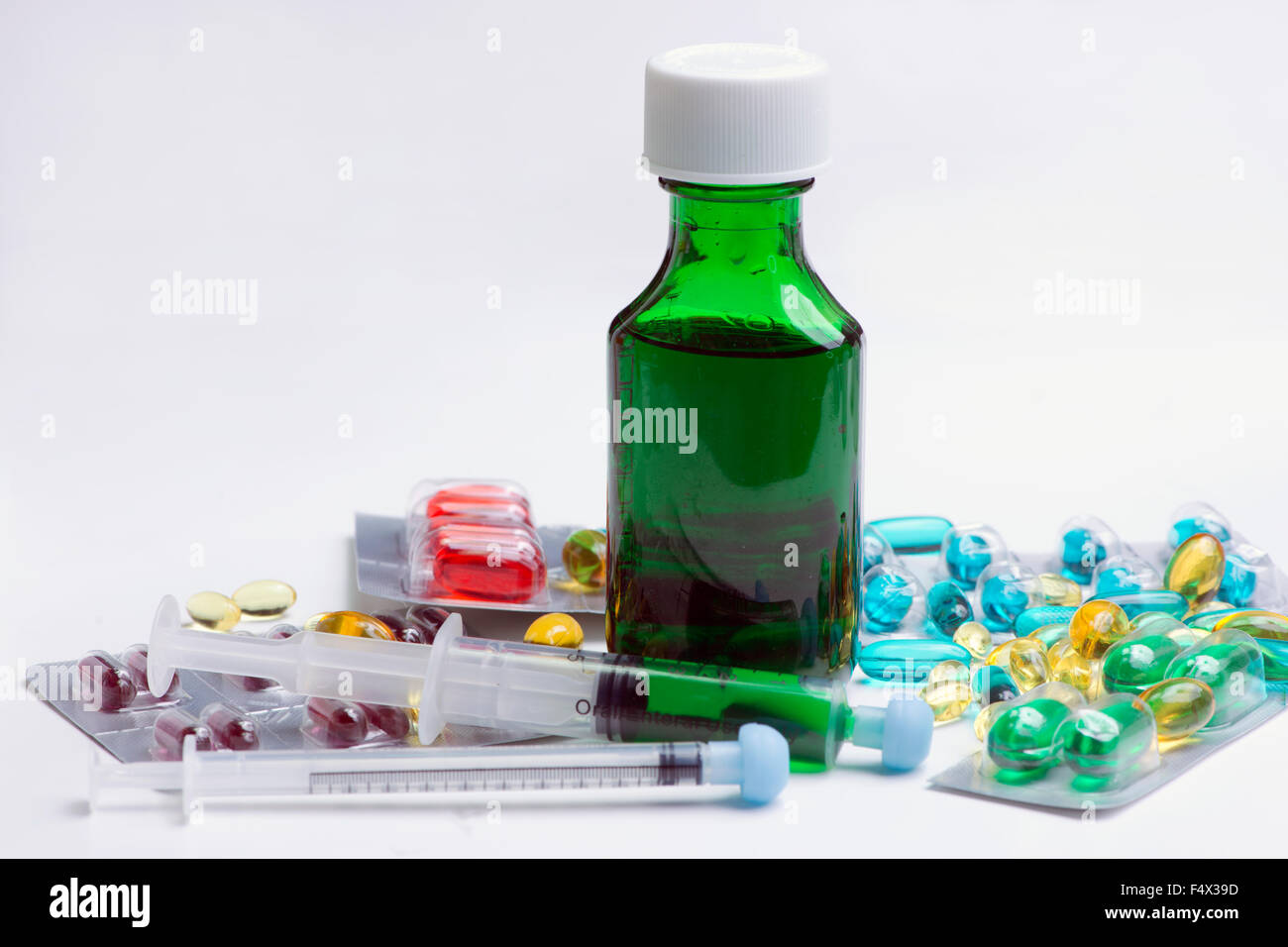 La toux vert bouteille avec des seringues orales et cold remedy capsules. Banque D'Images