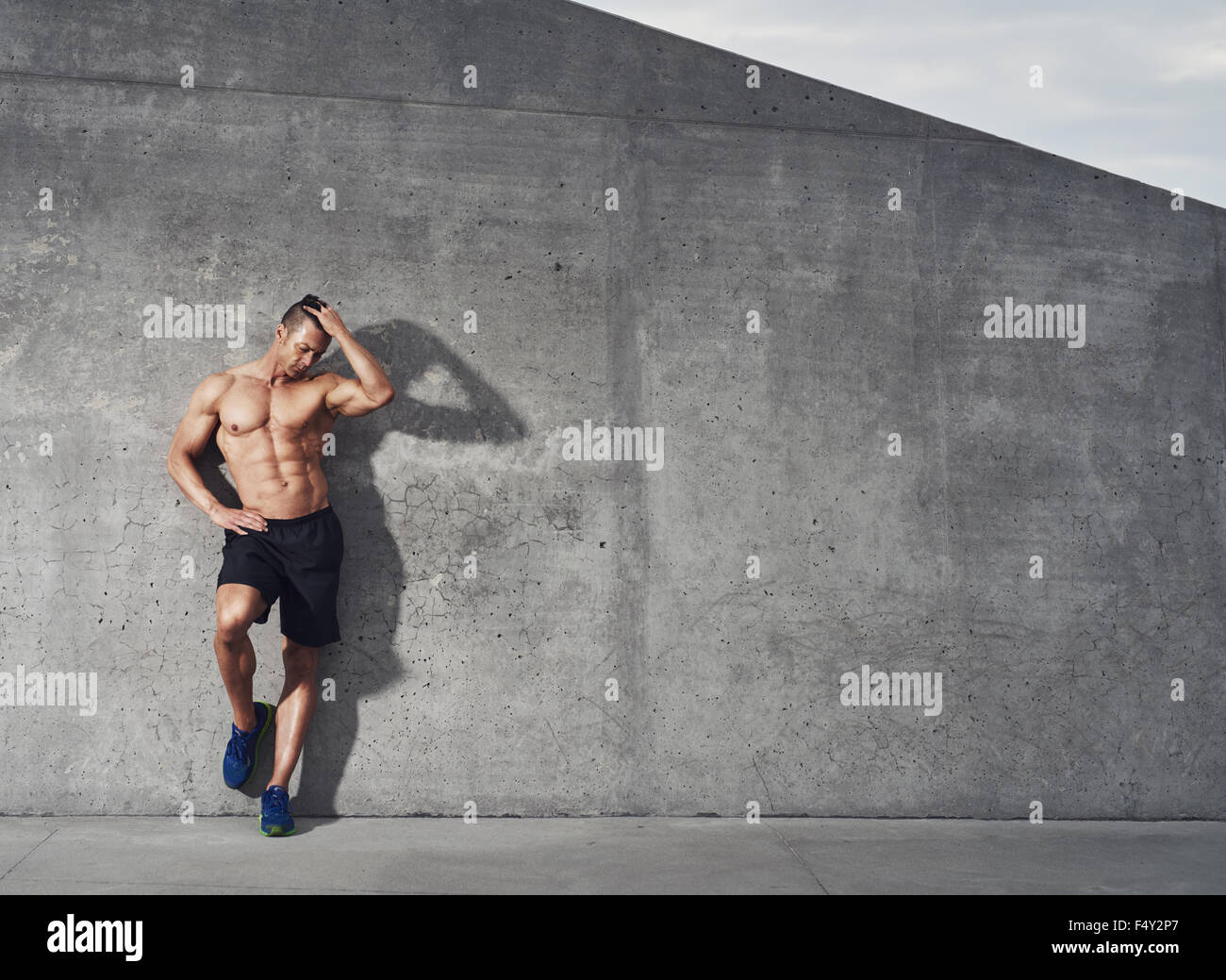 En bonne santé et de remise en forme, portrait modèle masculin debout contre le mur à la Chambre, pour l'exemplaire de l'espace. Banque D'Images