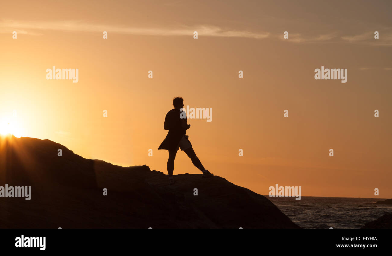 Silhouette d'une femme debout devant le coucher de soleil sur le littoral de la Californie. Banque D'Images
