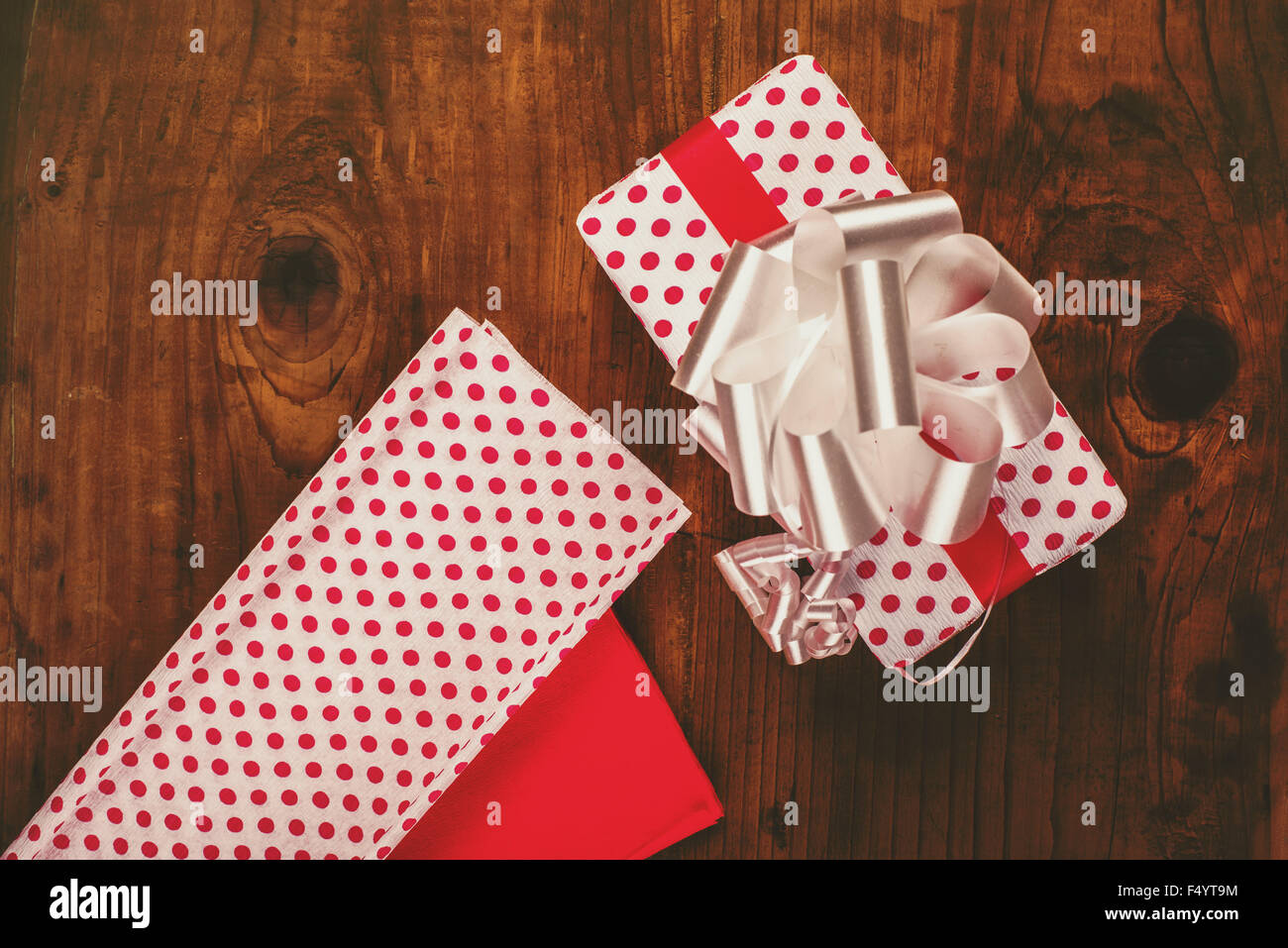 Cadeaux de Noël et présente l'emballage, l'enveloppé ox avec papillon et décoratives sur papier à points polka bureau en bois, vue du dessus, retro Banque D'Images