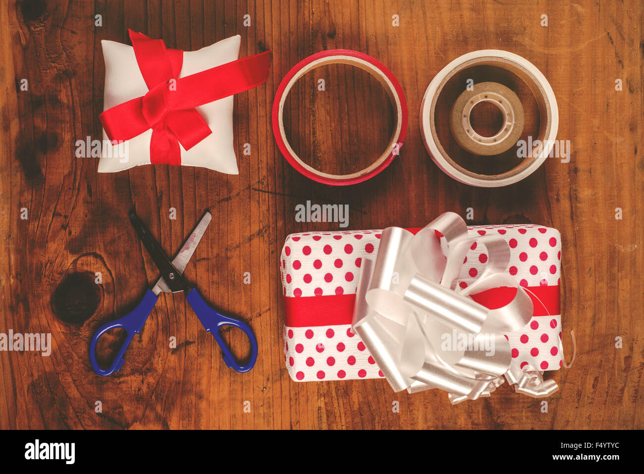 Cadeaux de Noël et présente l'emballage, l'assortiment polka dotted décoratif papier, ciseaux et ruban bandes sur un bureau en bois, haut de la vie Banque D'Images
