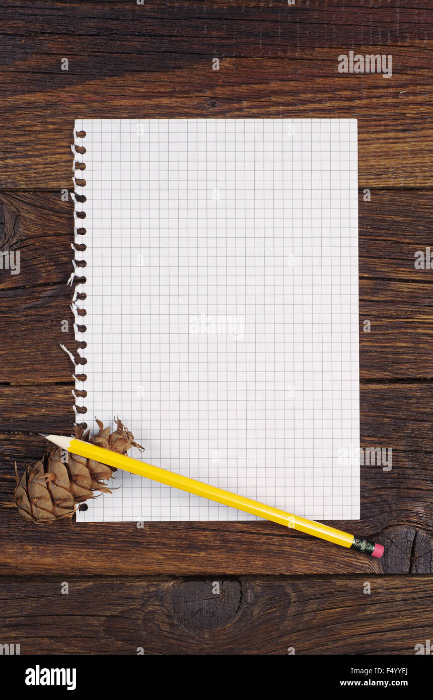Page vierge d'un ordinateur portable, un crayon et un cône de pin sur la vieille table en bois. Vue d'en haut Banque D'Images