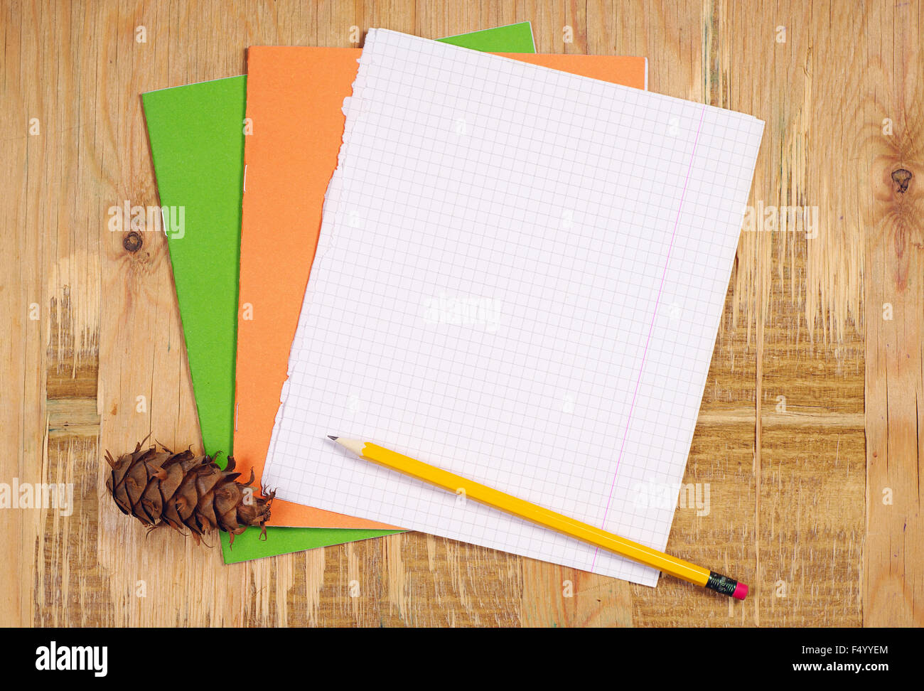 Cahiers scolaires, feuille blanche, un crayon et un cône de pin sur la vieille table en bois. Vue d'en haut Banque D'Images