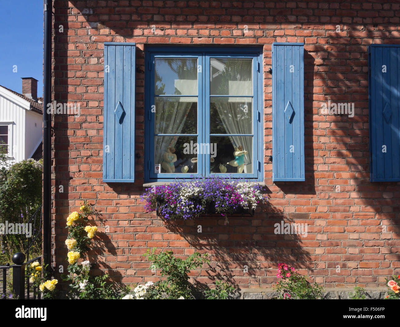 Détail de l'idyllique maison en brique rouge, bleu châssis de fenêtre, volets roulants, fleurs bleu à la case, été impression de Drobak Norvège Banque D'Images