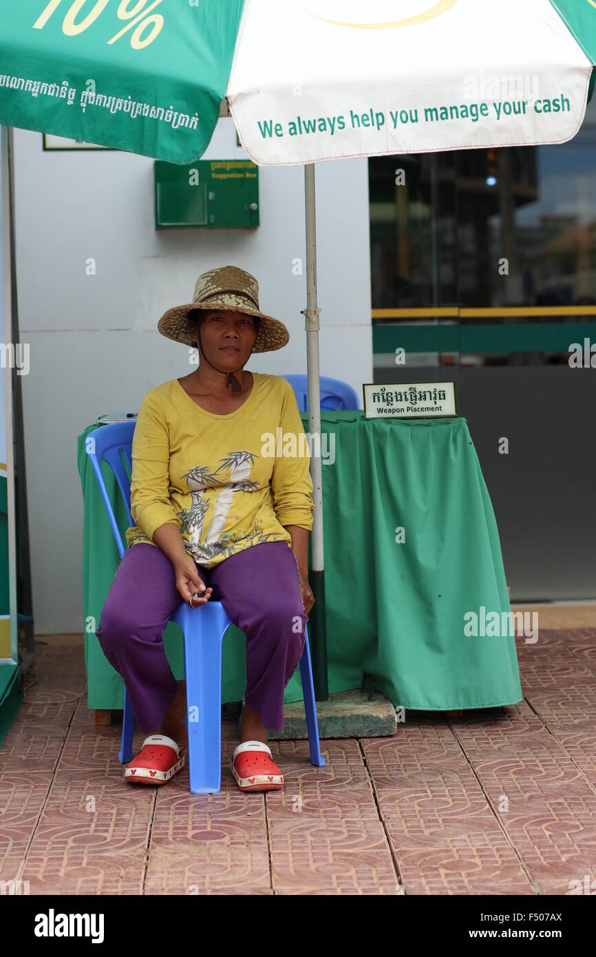 Femme sous un parasol qui lit 'nous vous aider à gérer votre trésorerie' garder le bureau de placer armes avant d'entrer dans le bâtiment. Banque D'Images