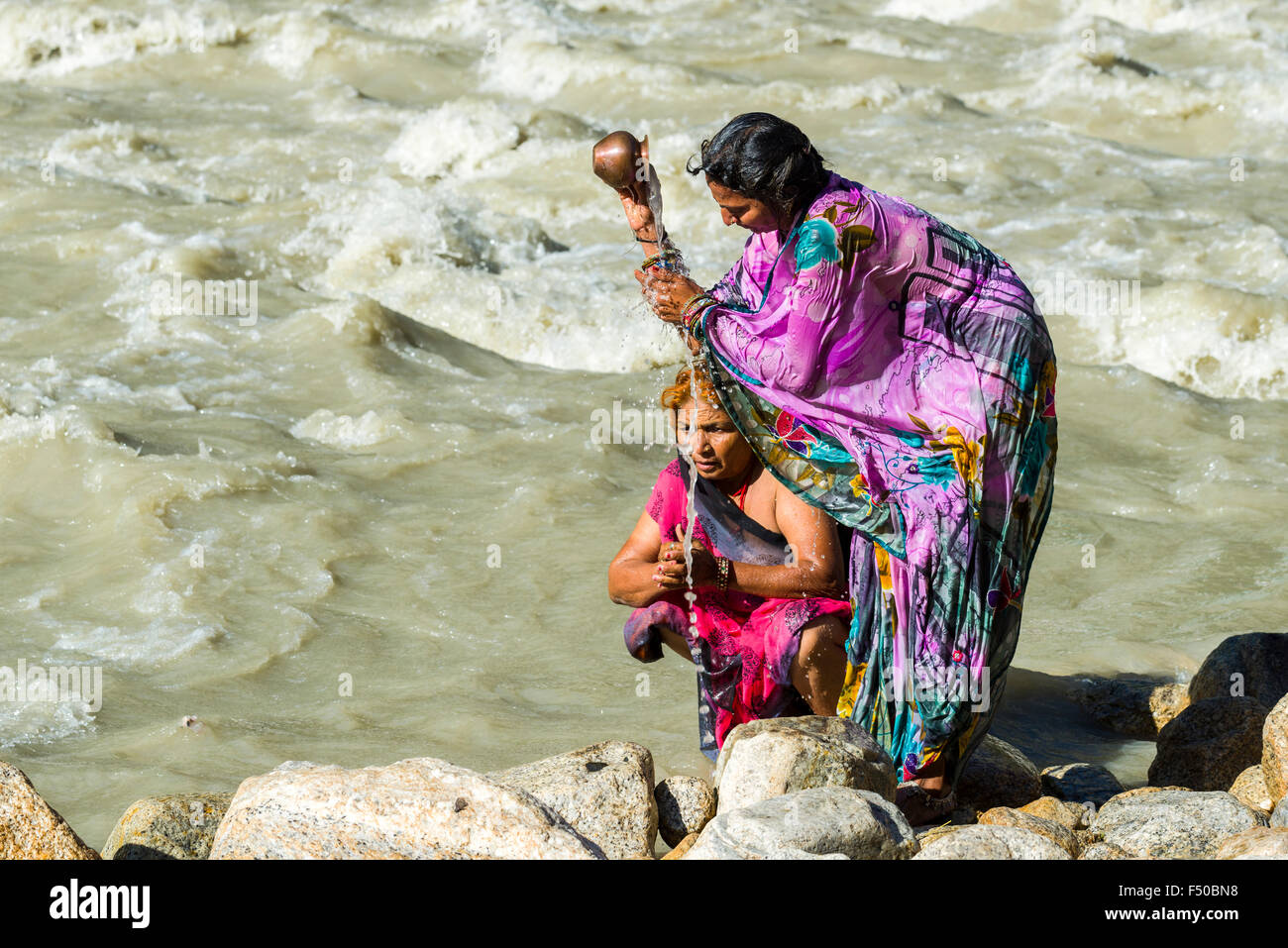 Deux femmes pèlerins dans les rives du Gange sont en train de prendre une douche avec l'eau sainte Banque D'Images