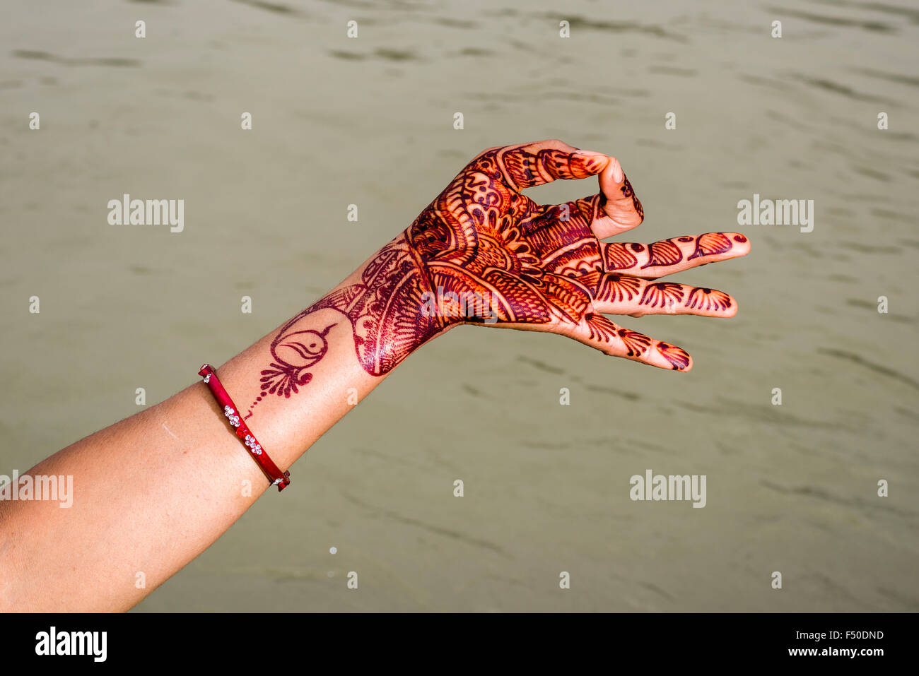 Une main peinte au henné est montrant le mudra gyan mudra à les ghats du fleuve saint Ganges Banque D'Images