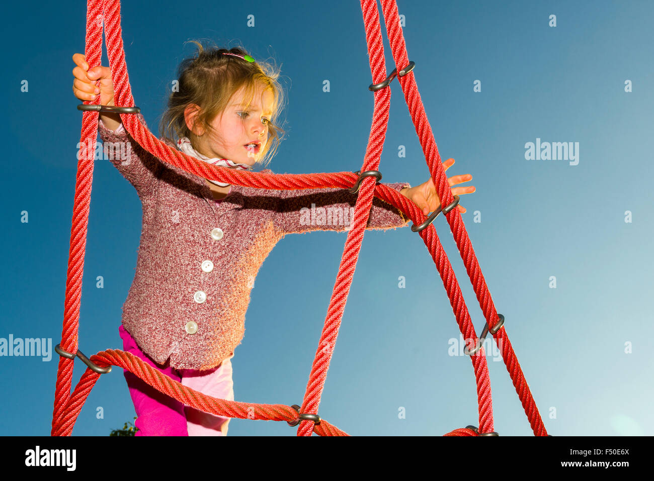 Une fillette de trois ans est un échafaudage de corde d'escalade Banque D'Images