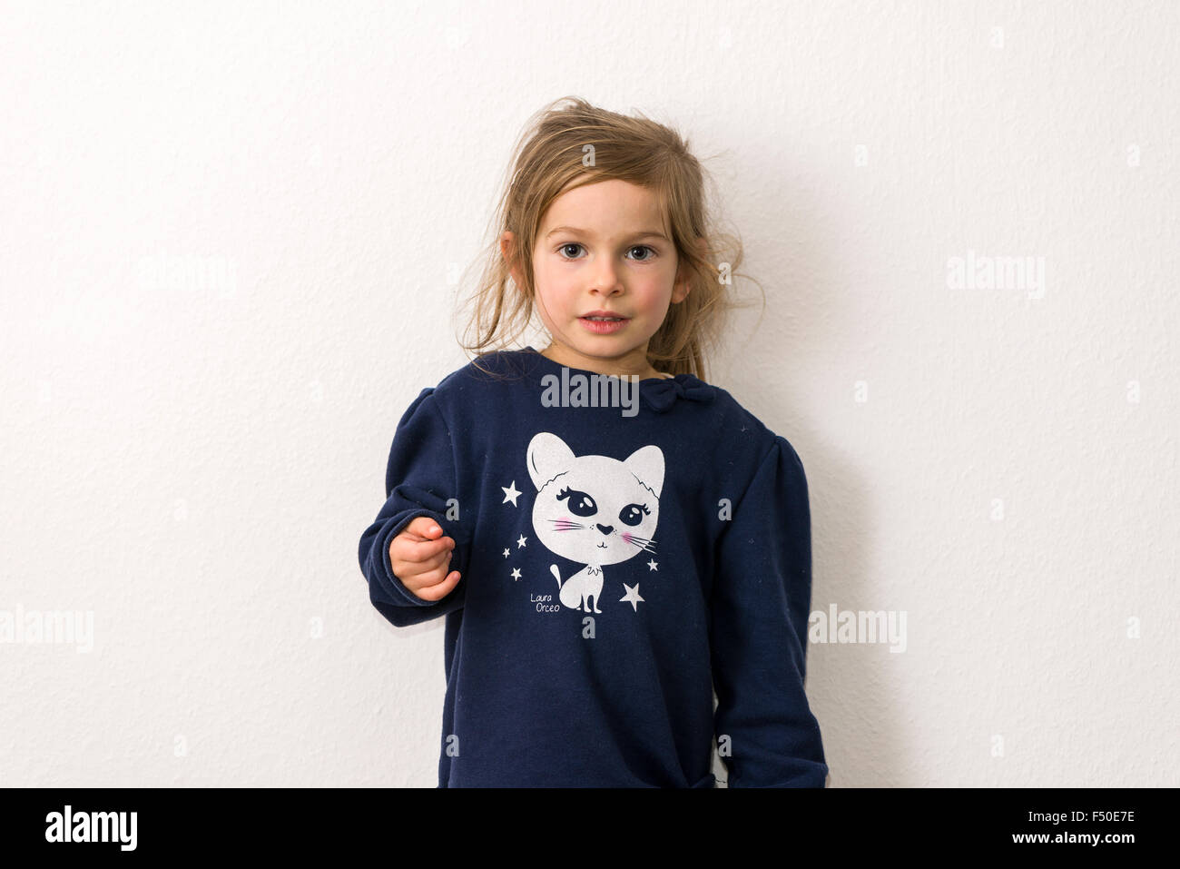 Le portrait d'une fillette de trois ans avec les cheveux blonds, vêtu d'un pull bleu avec la photo d'un chat blanc Banque D'Images