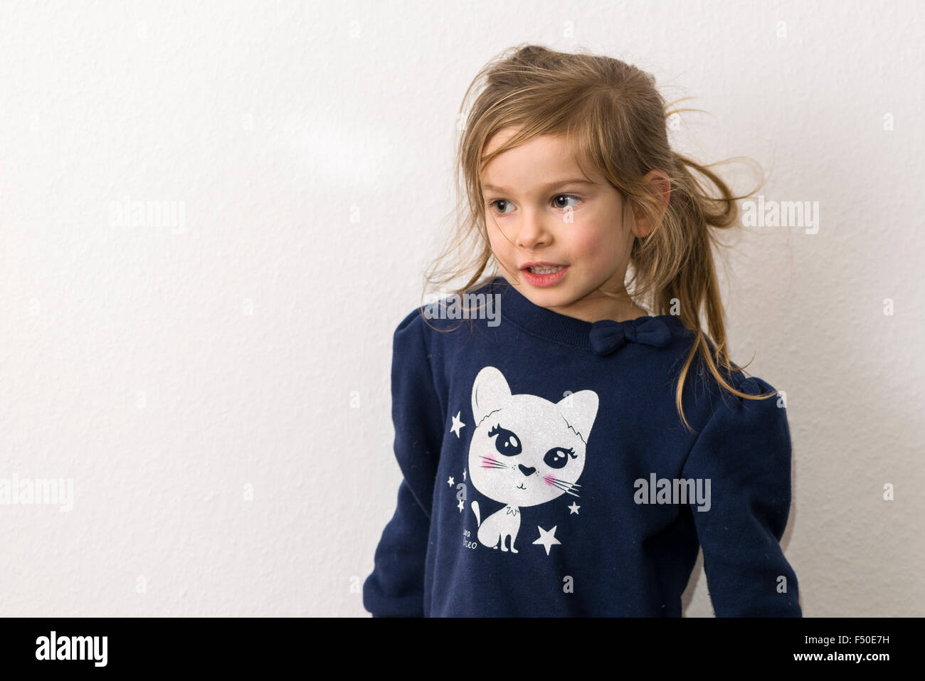 Un Portrait of a smiling fillette de trois ans avec les cheveux blonds, vêtu d'un pull bleu avec la photo d'un chat blanc Banque D'Images