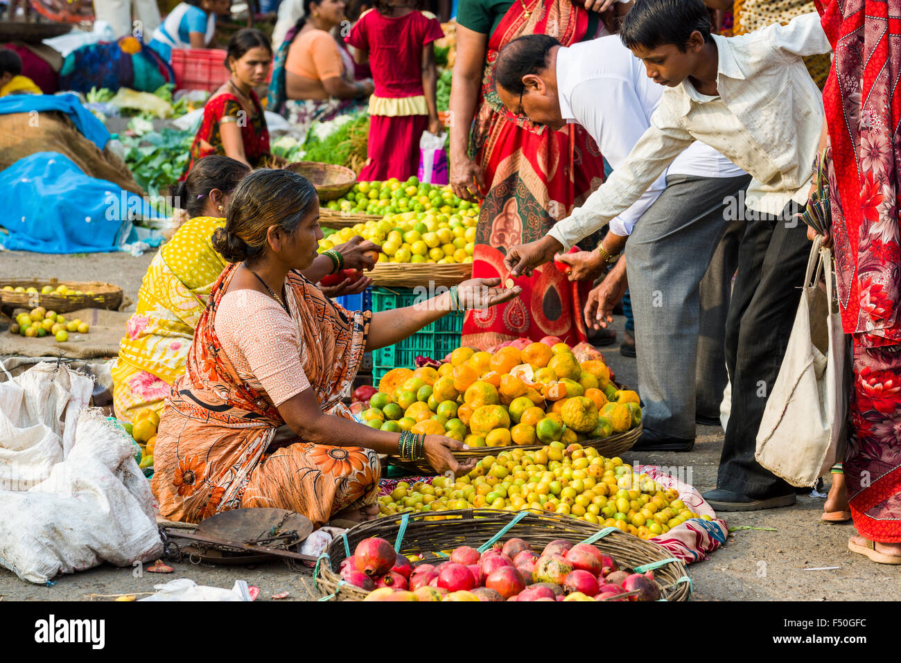 Une femme vend des oranges, citrons verts et pommes à l'hebdomadaire de légumes du marché Banque D'Images