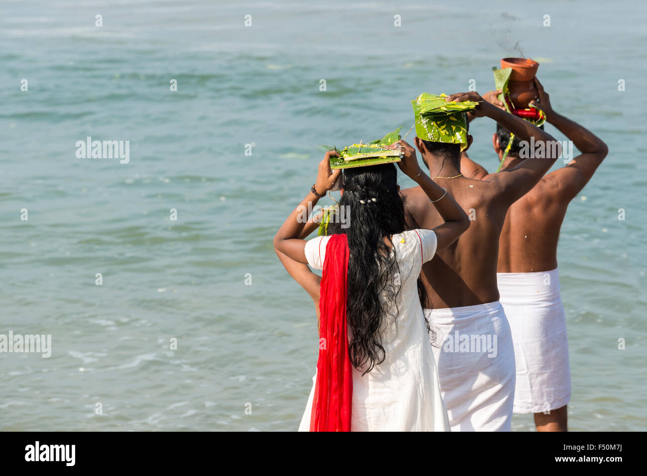 Quatre pèlerins sont face à la mer dans le cadre de l'veli tarpanam pooja, un rituel d'adieu pour les membres de la famille est décédé Banque D'Images